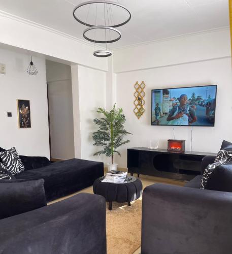 a living room with black furniture and a flat screen tv at New Haven 3 in Kisii