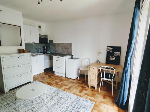 une cuisine avec des placards blancs, un bureau et une table dans l'établissement Agréable studio proche plages et commerces, au Pradet