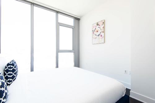 a white bedroom with a bed and a window at Sky-Rise Apartments in Los Angeles