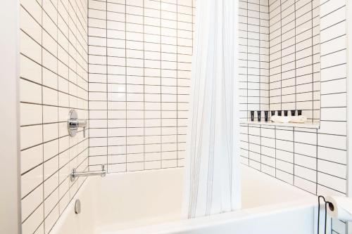 a white tiled bathroom with a tub and a shower at Sky-Rise Apartments in Los Angeles