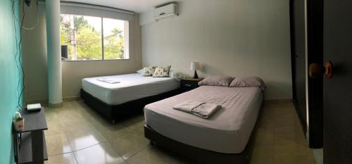 1 dormitorio con 2 camas y ventana en Hotel Aqua lux, en Medellín