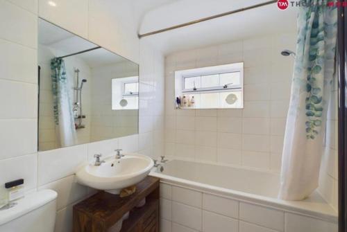 ein weißes Badezimmer mit einem Waschbecken, einer Badewanne und einem Waschbecken in der Unterkunft relaxed and peaceful in St Ives