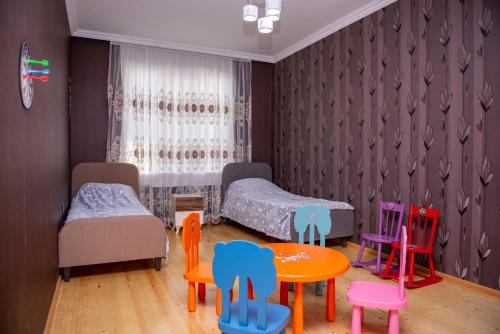 a room with two beds and colorful chairs at Harmony Haven House in Sheki