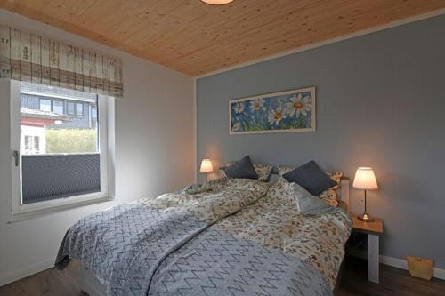 a bedroom with a bed with two lamps and a window at Ferienhaus in Schlagsdorf auf Fehmarn in Schlagsdorf