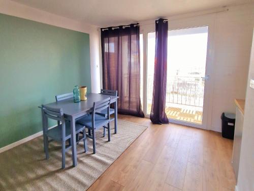 une salle à manger avec une table et des chaises et une grande fenêtre dans l'établissement Appartement de plage 16-17, à Biscarrosse-Plage