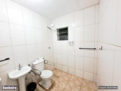 a white bathroom with a toilet and a sink at CASA DE VERANEIO PERUIBE in Peruíbe