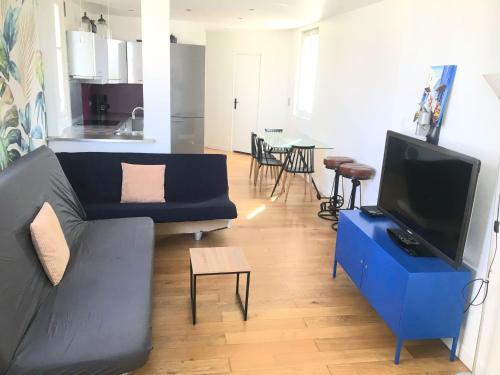 a living room with a blue couch and a tv at Logement de standing à 9min du centre de Paris in Colombes