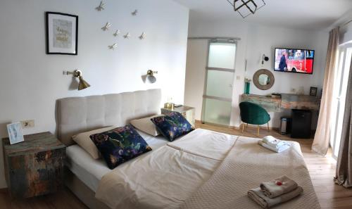 een slaapkamer met een wit bed en een groene stoel bij Rooms and Apartments Riviera in Rab