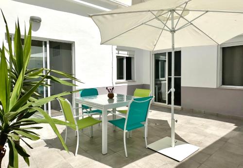 una mesa blanca y sillas con sombrilla en el patio en Bonita Planta baja con patio en 1ª línea de playa, en Puerto Sagunto