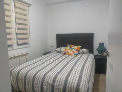 a bed with a striped comforter in a bedroom at PIso recién reformado y espacioso in Haro