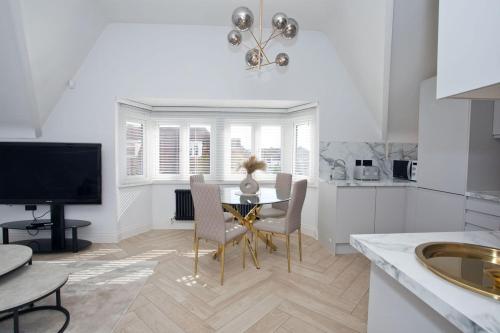cocina con mesa y sillas y TV en Ultra Stylish Apt set in an affluent location, en Poole