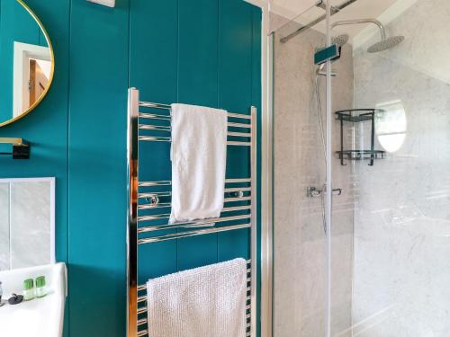 a bathroom with blue walls and a shower with towels at Maple in Swadlincote