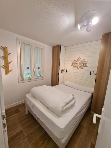 a bedroom with a white bed and two windows at Escapade Montagne en Famille, appartement cosy avec piscine couverte in Bielle