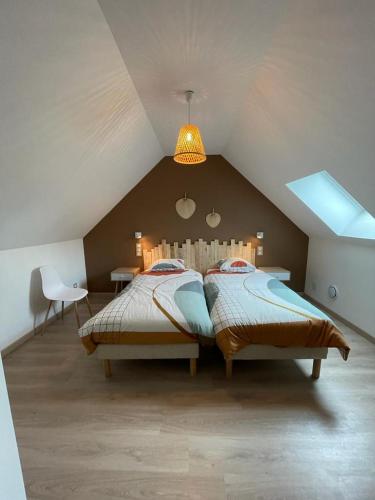 une chambre avec deux lits dans un grenier dans l'établissement gîte Les Mondaines-Les Tourterelles, à Favières
