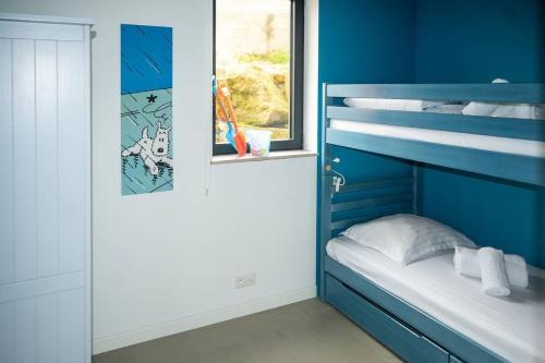 - une chambre avec un lit superposé bleu et une fenêtre dans l'établissement Petite dune, Port Blanc Vue Mer 20 m, à Penvénan