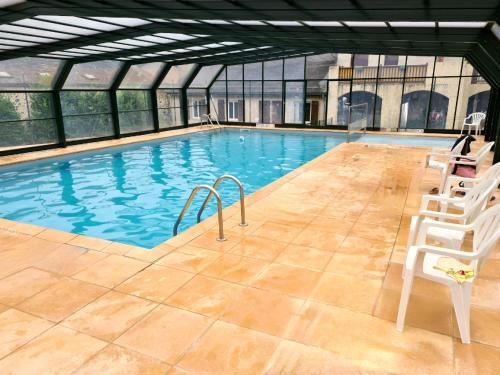 - une grande piscine avec 2 chaises blanches dans l'établissement Escapade Montagne en Famille, appartement cosy avec piscine couverte, à Bielle