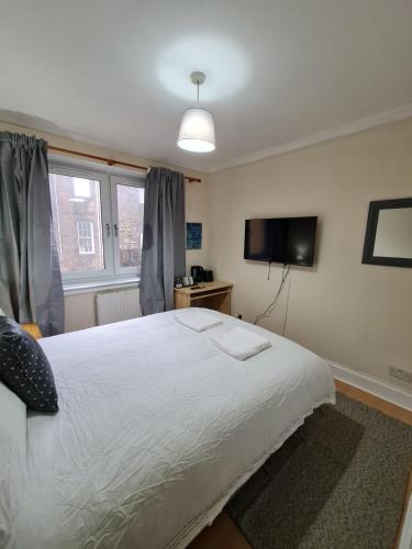 a bedroom with a large white bed and a television at Arthur St Rooms in Edinburgh