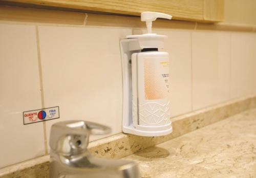 ロンドリーナにあるComfort Suites Londrinaのキッチンのシンクの壁に取り付けられた石鹸ディスペンサー