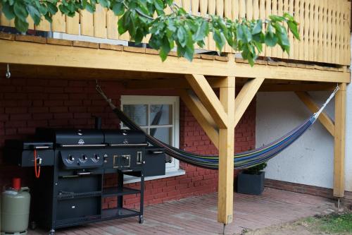 a grill under a porch with a hammock under it at Apart & Heu Hotel Hofmann in Niederaula