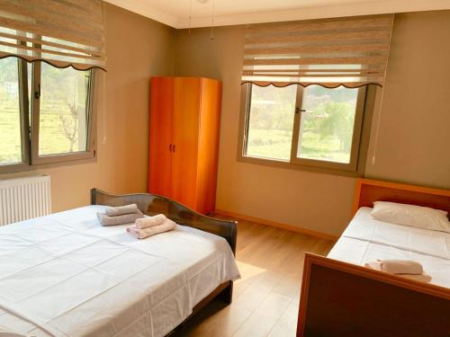 two beds in a room with two windows at Zeni Villa - Fırtına Deresinde mükemmel konaklama in Rize