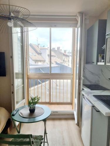 une cuisine avec une table devant une grande fenêtre dans l'établissement L'Aiglon de Foch 4#Accès FAC#, à Grenoble