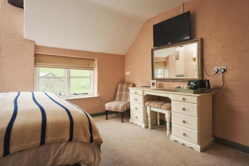 a bedroom with a desk and a dresser with a mirror at Blue Ball Inn in Lynmouth