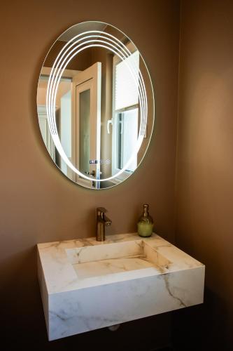 a bathroom with a marble sink and a round mirror at Apartment Onyx Carolyne in Bistriţa