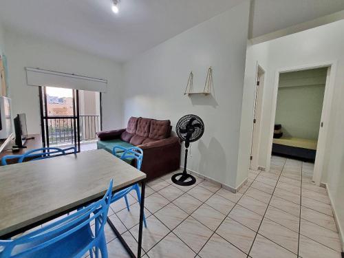 uma sala de estar com um sofá, uma mesa e uma ventoinha em Apto 01 dorm c/Ar Cond, Wi-Fi (rápido), Varanda, Piscina no Guarujá