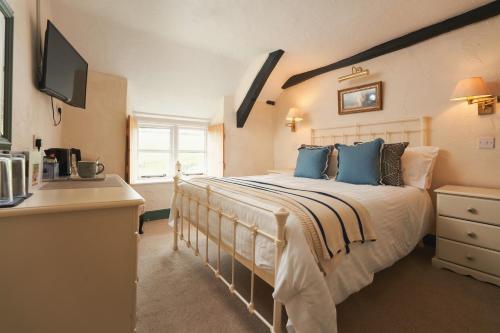 een slaapkamer met een groot bed met blauwe kussens bij Blue Ball Inn in Lynmouth