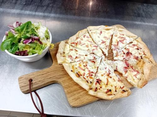 a pizza and a salad on a cutting board at The Originals City Hotel Artyster Clermont Ferrand in Clermont-Ferrand