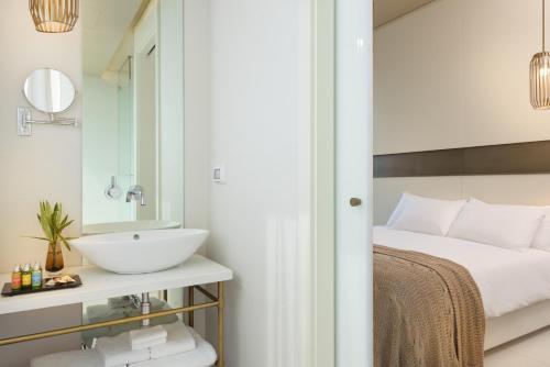 a bathroom with a sink and a bed with a mirror at Hotel Rothschild 22 in Tel Aviv