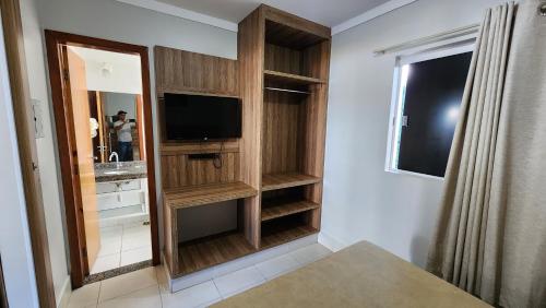 a bathroom with a tv and a mirror at Lacqua diRoma 1 - Apartamentos JN in Caldas Novas