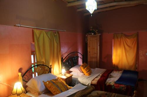 a bedroom with two beds and a table and two lamps at DAR Moha dades in Aït Ougliff
