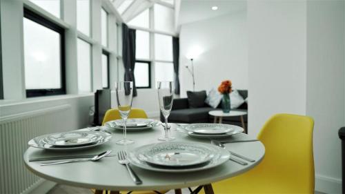 uma mesa de jantar com pratos e copos de vinho em Sapphire House Apartments em Telford