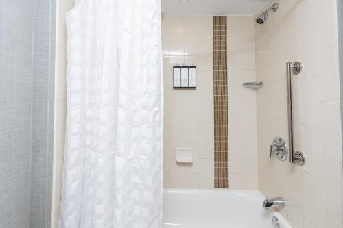 a bathroom with a shower with a white shower curtain at Hyatt Place Greenville/Haywood in Greenville