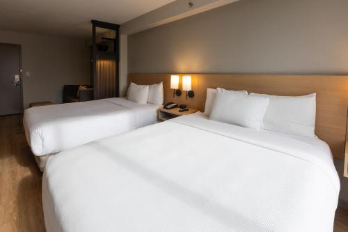 two large white beds in a hotel room at Hyatt Place Greenville/Haywood in Greenville