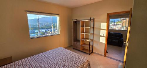 una camera da letto con un letto e una finestra di Apartamento mobiliado com vista da linda Serra Mantiqueira a Cruzeiro