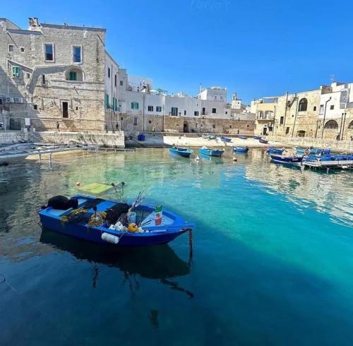 a blue boat in a body of water with buildings at Dimora Barbacana in Monopoli