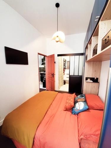 une chambre avec un grand lit avec une couverture orange dans l'établissement Ravissant appartement entièrement rénové T2, proche de la rue Saint Catherine, à Bordeaux
