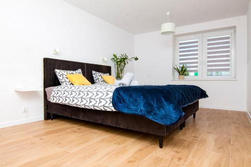 a bedroom with a bed with a blue blanket on it at Apartament Chełm City in Chełm