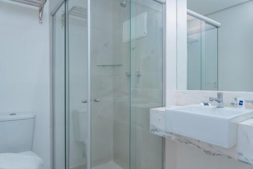 a bathroom with a glass shower and a sink at Hotel Praia Bonita Jangadeiros Pajuçara in Maceió