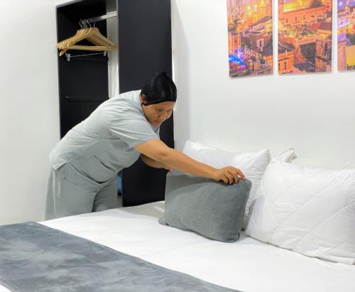 a woman putting a pillow on a bed at Hotel El Marqués De Manga in Cartagena de Indias