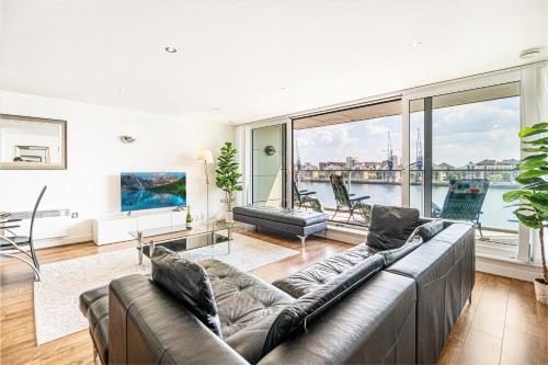 a living room with a couch and a large window at Spacious Excel London Apartment with Balcony, River View and Parking Sleeps 8 in London