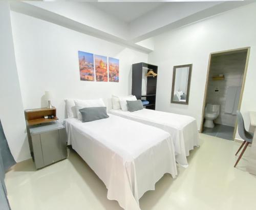 a white bedroom with two beds and a mirror at Hotel El Marqués De Manga in Cartagena de Indias