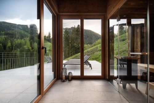a room with glass doors and a balcony with a bench at DasKöniglich Luxury Alpine Chalet - Mühlbach am Hochkönig in Mühlbach am Hochkönig