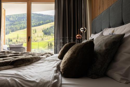a bed with pillows on it with a large window at DasKöniglich Luxury Alpine Chalet - Mühlbach am Hochkönig in Mühlbach am Hochkönig