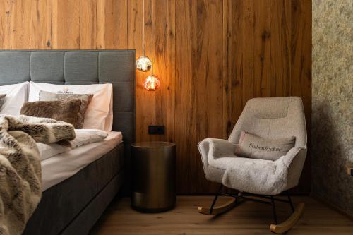 a bedroom with a chair next to a bed and a chair at DasKöniglich Luxury Alpine Chalet - Mühlbach am Hochkönig in Mühlbach am Hochkönig