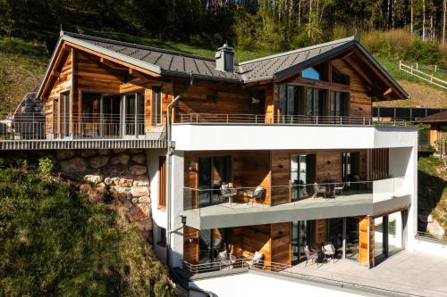 a house on a hill with a large deck at DasKöniglich Luxury Alpine Chalet - Mühlbach am Hochkönig in Mühlbach am Hochkönig