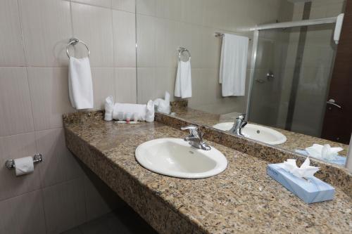 Cuenta con una encimera con 2 lavabos y un espejo. en Victoria Hotel and Suites Panama, en Panamá