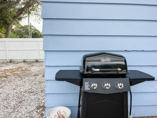 a barbecue grill sitting outside of a blue house at 10 min Lido Key Beach ~Coastal Cabana Hideout in Sarasota
